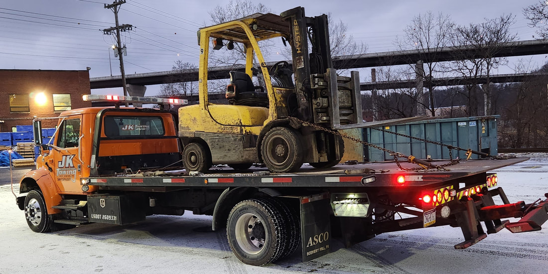 JK Towing's rollback truck transporting a forklift