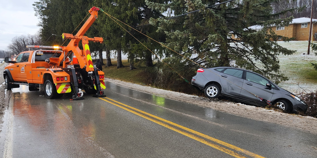 JK Towing's tow truck using its boom and winches to remove a car from a ditch